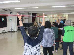 吹矢を持って腕を上に伸ばしている