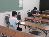 子どもと講師がノートに作文を書いている