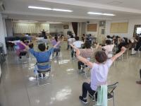 椅子に座って両手を広げて上にあげている