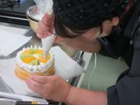 ケーキに絞り袋でクリームを飾っている
