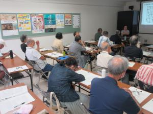 講師がスクリーンに資料を投影し説明している