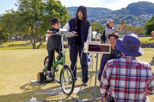 自転車発電を体験するこども