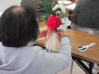 造花をしめ縄にくくりつけている